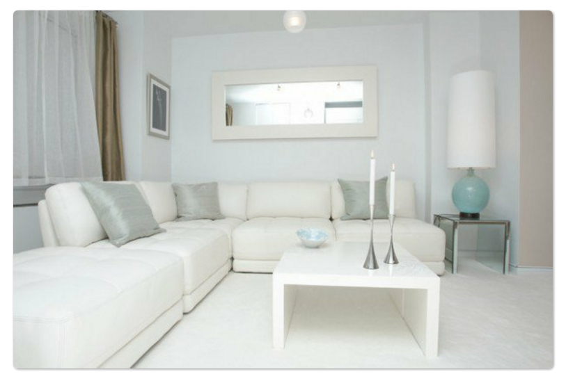 Decoracion minimalista con amplio sofá y tonos blancos
